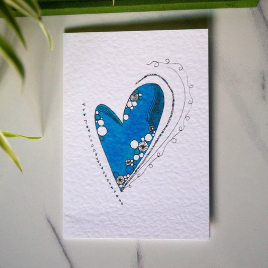 White textured greetings card featuring a blue illustrated heart with swirling and line details.
