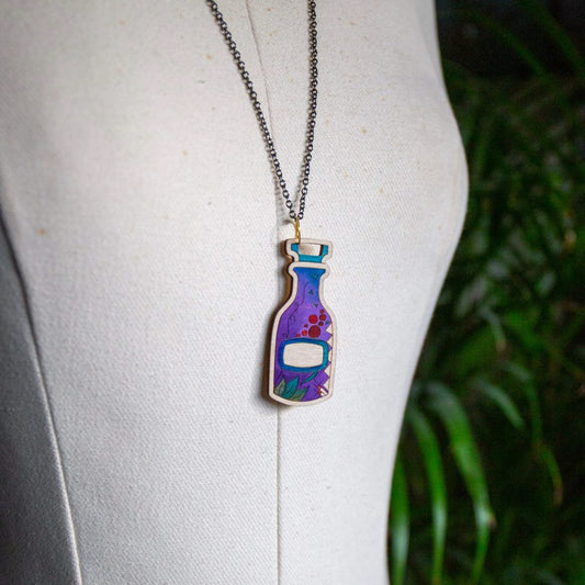 A purple wooden potion bottle necklace hanging on a white mannequin.
